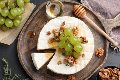 Brie cheese served with grapes, walnuts and honey on grey table, flat lay