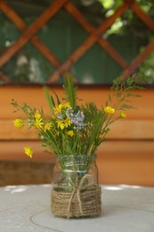 Bouquet of beautiful wildflowers in glass vase on table indoors