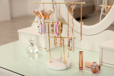 Holder with set of luxurious jewelry on white dressing table