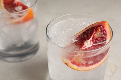 Delicious refreshing drink with sicilian orange and ice cubes on light table, closeup