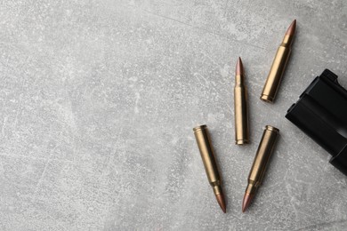 Bullets and handgun on light grey table, flat lay. Space for text