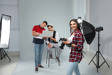 Photo of Professional photographer and assistant working with model in modern studio