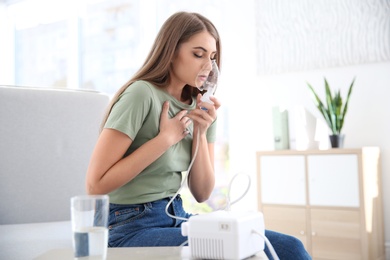 Young woman with asthma machine in light room