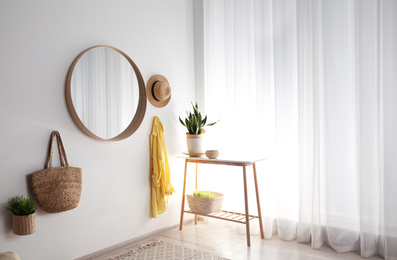 Round mirror with wooden frame on white wall in light room
