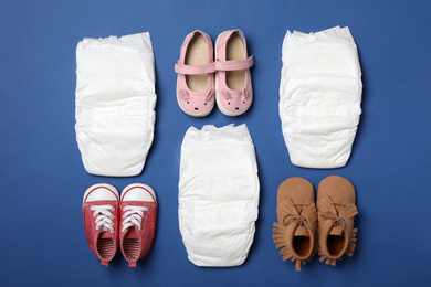 Photo of Diapers and baby accessories on blue background, flat lay