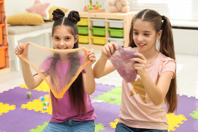 Happy girls playing with slime in room