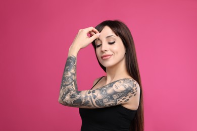 Woman with tattoos on arm against pink background