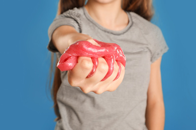 Preteen girl with slime on blue background, closeup