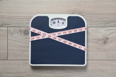 Scales and measuring tape on wooden background, top view. Weight loss