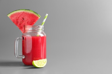 Tasty summer watermelon drink with lime in glass mason jar on grey background. Space for text