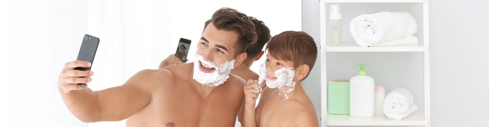 Father and son taking selfie while shaving in bathroom. Banner design