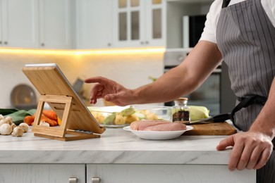 Man watching online cooking course via tablet in kitchen, closeup