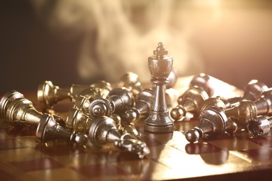 Photo of Chessboard with game pieces lit by lamp, closeup