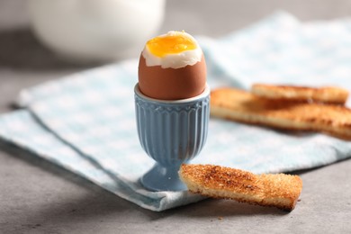 Tasty boiled chicken egg with toasted bread on grey table, closeup