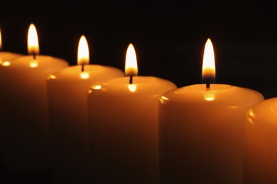 Burning candles on dark background, closeup. Memory day