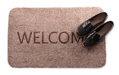Door mat with word WELCOME and shoes on white background, top view