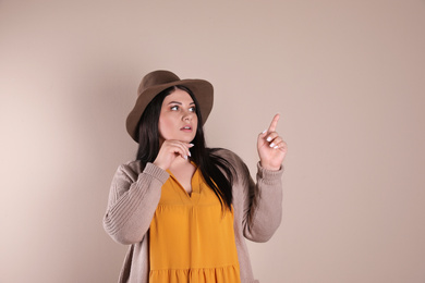 Emotional overweight woman posing on beige background. Plus size model