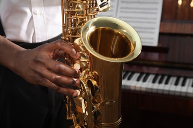 African-American man playing saxophone indoors, closeup. Talented musician