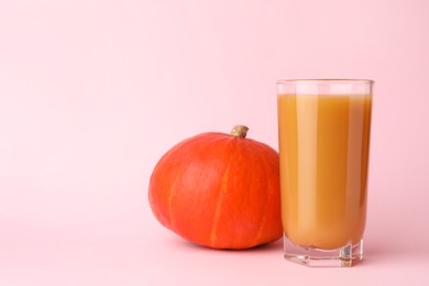 Photo of Tasty pumpkin juice in glass and whole pumpkin on pink background