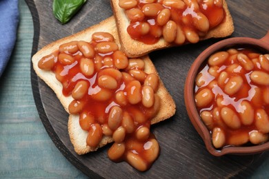 Toasts with delicious canned beans on light blue wooden table, top view