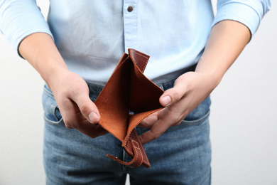 Photo of Man showing empty wallet on light background, closeup