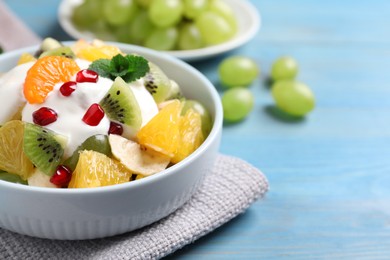 Delicious fruit salad on light blue wooden table, space for text
