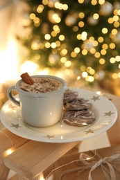 Tasty hot drink, cookies and Christmas lights in room