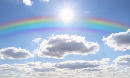 Beautiful rainbow in blue sky with white clouds on sunny day