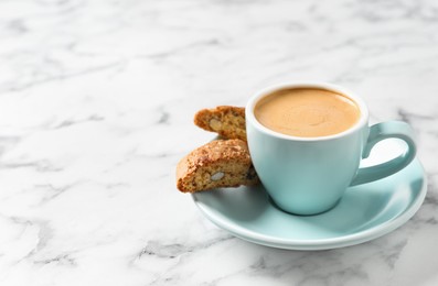 Tasty cantucci and cup of aromatic coffee on white marble table, space for text. Traditional Italian almond biscuits