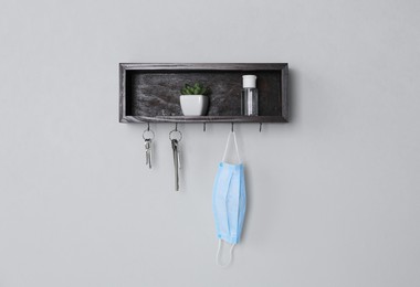 Wooden hanger for keys with different stuff on light grey wall