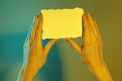 Photo of Man holding sheet of paper on color background, closeup and space for text. Color tone effect
