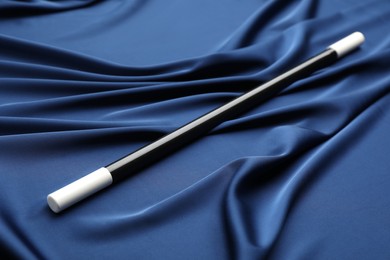 Beautiful black magic wand on blue fabric