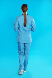 Doctor in uniform walking on blue background