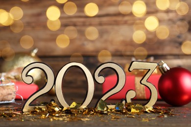Number 2023 and festive decor on wooden table, bokeh effect. Happy New Year