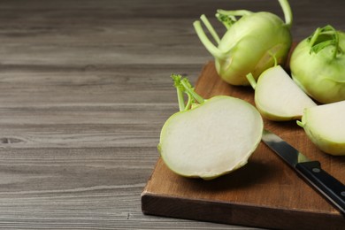Whole and cut kohlrabi plants on wooden table. Space for text