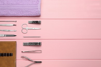 Photo of Set of manicure tools, towel and case on pink wooden background, flat lay. Space for text