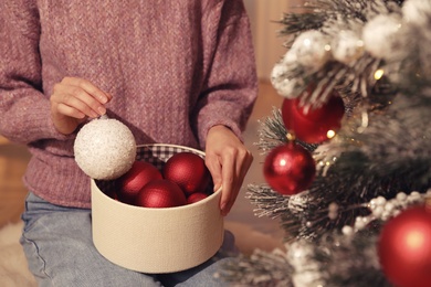 Woman decorating Christmas tree at home, closeup