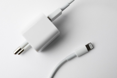 Photo of Charging cable and adapter on white background, top view