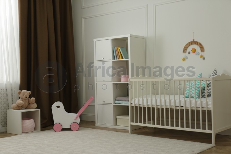 Cute baby room interior with stylish furniture and toys