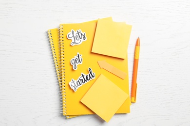 Sheets of paper with phrase Let's Get Started and stationery on white table, flat lay