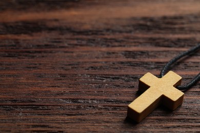 Wooden Christian cross on table, closeup. Space for text