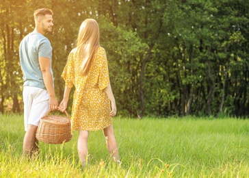 Young couple with picnic basket on green lawn