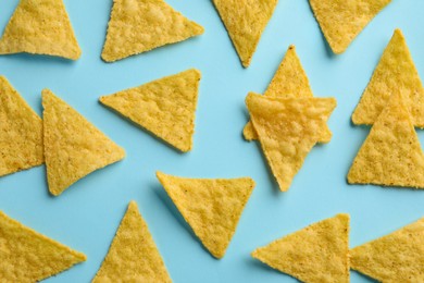 Photo of Flat lay composition of tasty tortilla chips (nachos) on light blue background