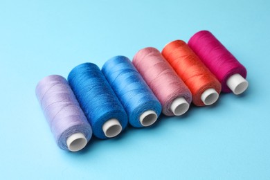 Set of different colorful sewing threads on light blue background
