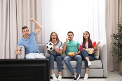 Group of people watching soccer match on TV at home