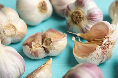 Fresh unpeeled garlic bulbs and cloves on light blue wooden table, closeup. Organic product