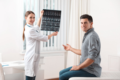 Orthopedist showing X-ray picture to patient in clinic