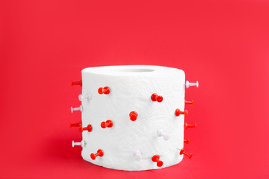 Roll of toilet paper with pins on red background. Hemorrhoid problems