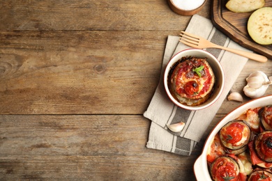 Baked eggplant with tomatoes, cheese and basil served on wooden table, flat lay. Space for text
