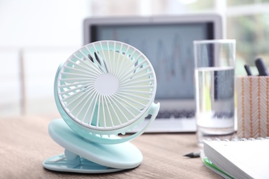 Modern portable fan on wooden table in office. Summer heat